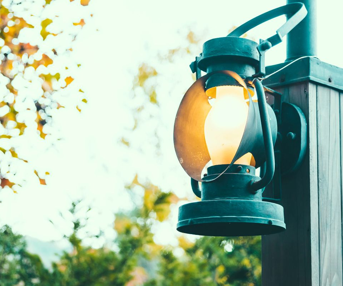 Outdoor lantern-style light fixture on wooden post.
