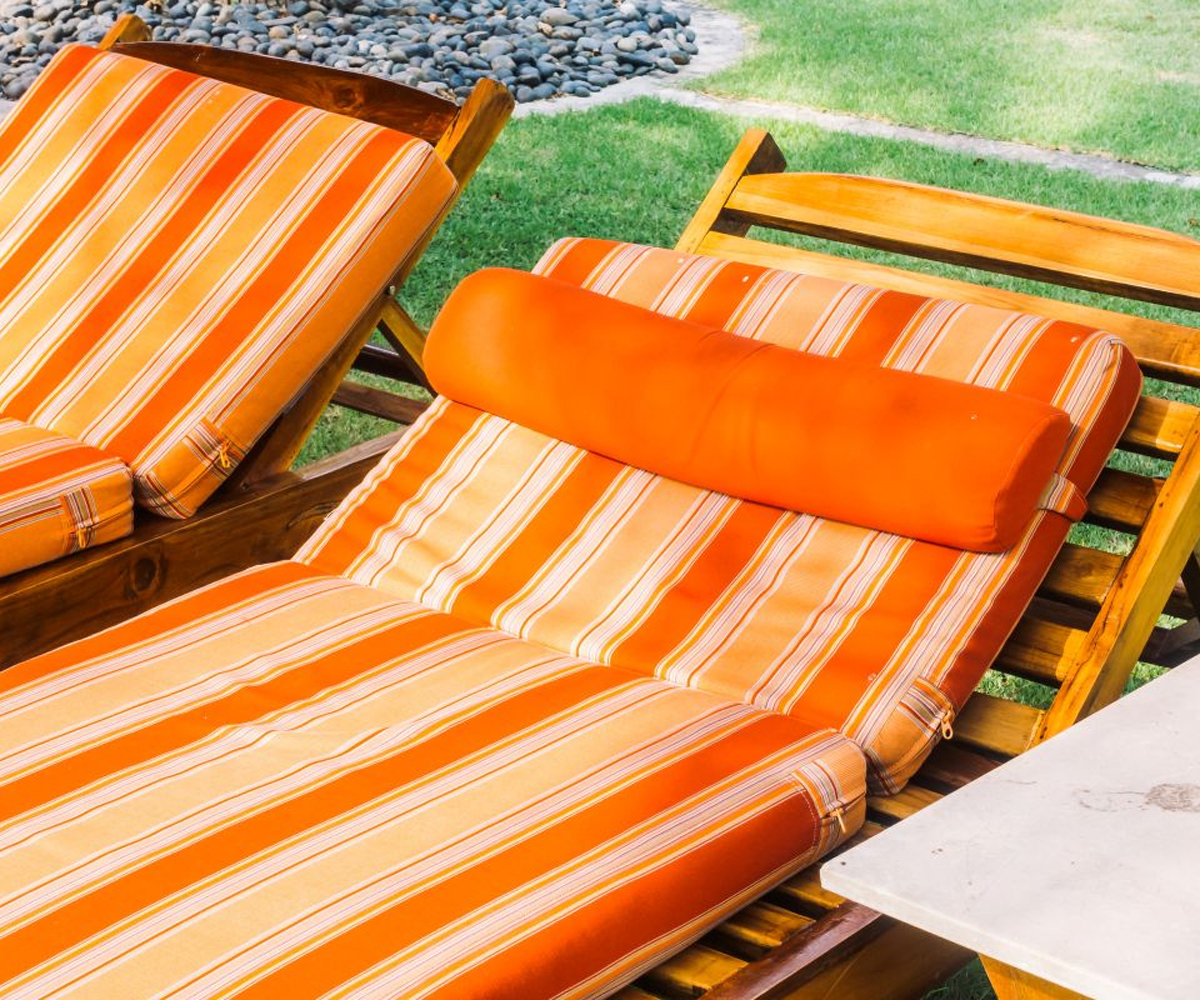 Outdoor lounge chair with orange striped cushions.